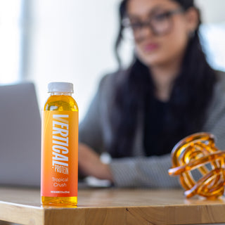 Picture of person with vertical protein water bottle on desk